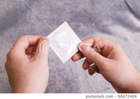 Condom in hand on a gray background Condom in hand on a gray background 88672409
