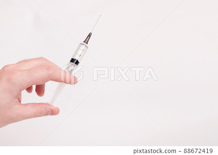 Syringe in hand on white background closeup Syringe in hand on white background closeup 88672419