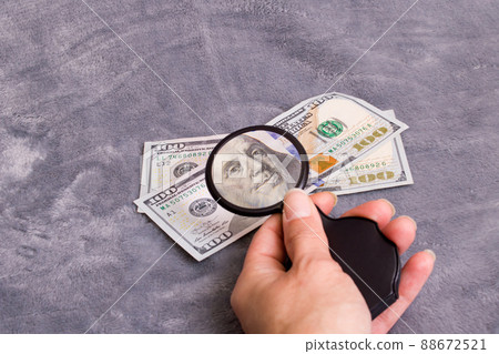 Checking dollar bill for authenticity with magnifying glass Checking dollar bill for authenticity with magnifying glass 88672521