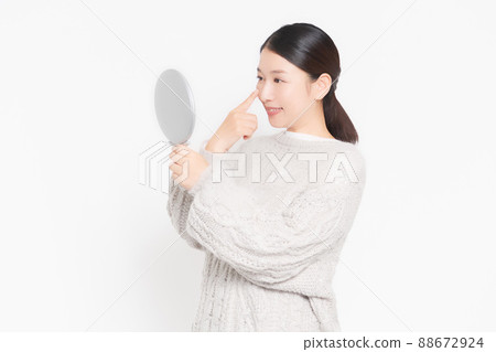 A woman checking her skin in the mirror A woman checking her skin in the mirror 88672924