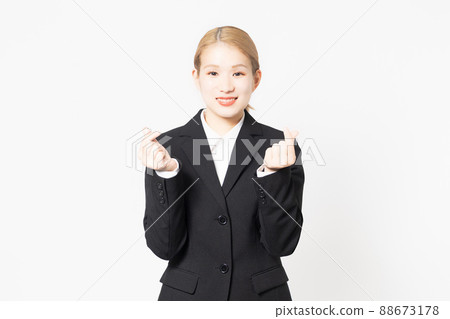 A woman in a jacket that makes a heart shape by hand 88673178