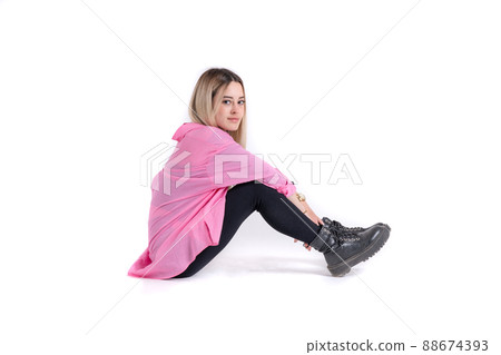 Young blonde woman sitting on floor posing and looking at camera Young blonde woman sitting on floor posing and looking at camera 88674393