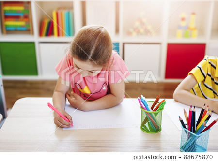 Schoolgirl in the classroom sitting at the tables and writing a lesson. 88675870