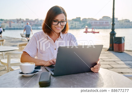 Smiling middle aged business woman in cafe with laptop 88677277