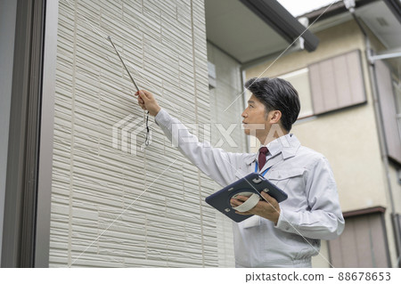 Image of construction management for a man in work clothes checking the outer wall with a pal hammer 88678653