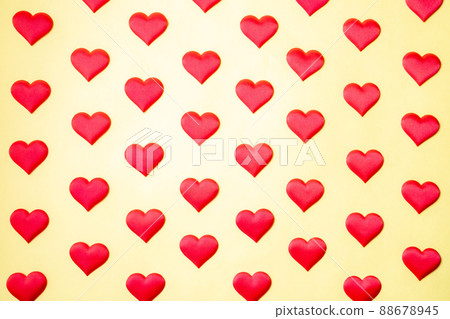 A lot of identical red silk hearts lying staggered on a yellow background. Symbol of love, tenderness and passion A lot of identical red silk hearts lying staggered on a yellow background. Symbol of love, tenderness and passion 88678945