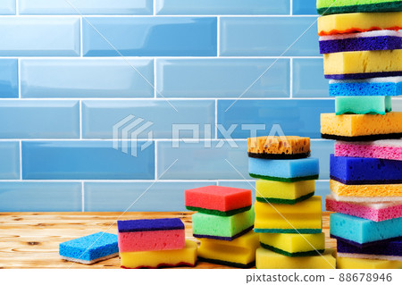 Pile of household cleaning sponges against blue tile wall Pile of household cleaning sponges against blue tile wall 88678946