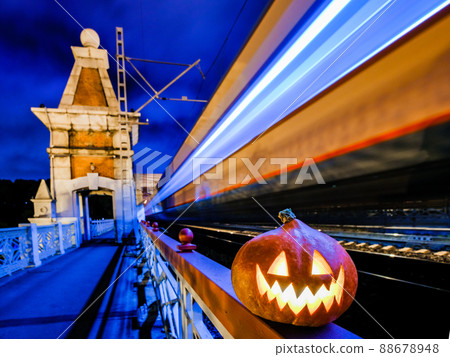 Halloween pumpkin with a glowing grimace at night on the railway bridge. Halloween pumpkin with a glowing grimace at night on the railway bridge. 88678948
