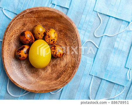 COVID-19 Flat lay. Colored Easter eggs on a background of blue medical masks COVID-19 Flat lay. Colored Easter eggs on a background of blue medical masks 88678951