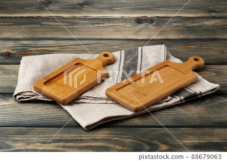 Wooden board with kitchen napkin on dark wooden table Wooden board with kitchen napkin on dark wooden table 88679063