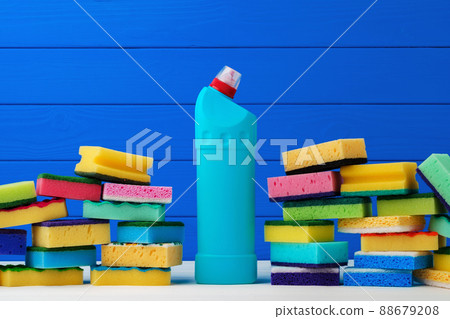 Stack of new cleaning sponges and liquid detergent against blue wooden background 88679208