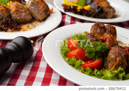 Cooked meat with fresh vegetable salad on a white plate 88679432
