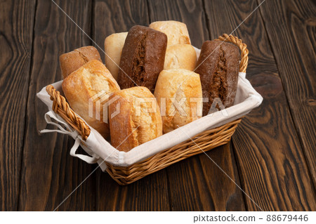 Fresh wheat and rye bread in a wicker basket on a brown wooden table Fresh wheat and rye bread in a wicker basket on a brown wooden table 88679446