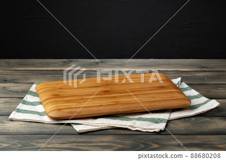 Wooden board with kitchen napkin on dark wooden table Wooden board with kitchen napkin on dark wooden table 88680208
