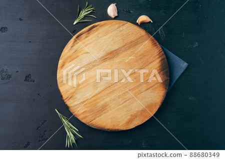 Empty wooden board with garlic and rosemary on black background Empty wooden board with garlic and rosemary on black background 88680349