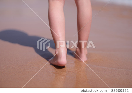 Wet bare feet walk along beach along sea closeup Wet bare feet walk along beach along sea closeup 88680351