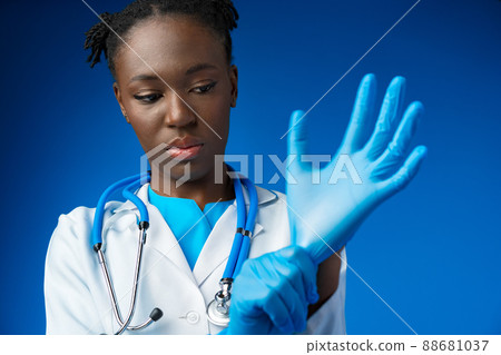 Black female doctor wears sterile blue gloves 88681037
