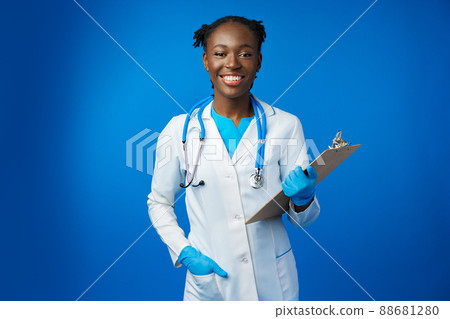 Portrait of happy african medical intern woman doctor with clipboard in blue studio 88681280