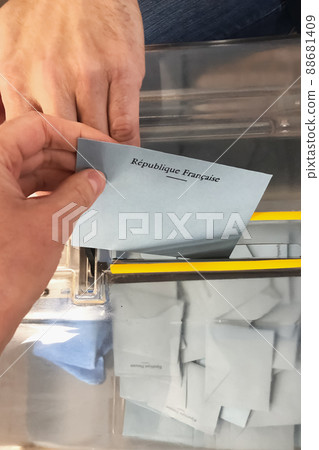 A voter throws an envelope with a candidate into the ballot box. Translation Republic of France A voter throws an envelope with a candidate into the ballot box. Translation Republic of France 88681409