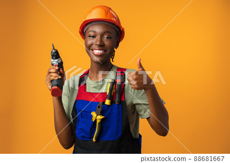 Smiling young african american woman in hardhat holding screwdriver tool in studio 88681667