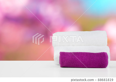 Stacked white spa towels on table against blurred background Stacked white spa towels on table against blurred background 88681819