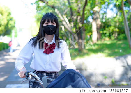 戴布口罩騎自行車上學的高中女生 住宅區 市區 美麗的清新綠色 戴布口罩騎自行車上學的高中女生 住宅區 市區 美麗的清新綠色 88681827