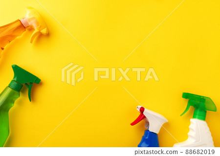 Cleaning detergent spray bottles on yellow background top view 88682019