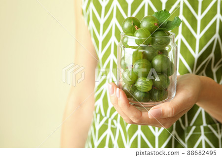 Woman in apron holds jar of gooseberry, close up 88682495