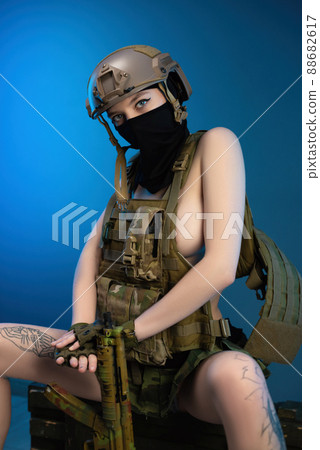 sexy girl soldier in a helmet, armed with an automatic rifle, in military clothes on a blue background 88682617