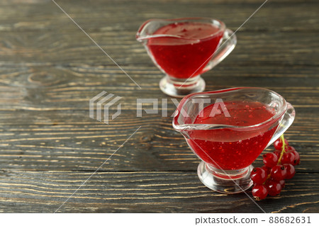 Sauce boats with cranberry sauce and cranberry on wooden background Sauce boats with cranberry sauce and cranberry on wooden background 88682631
