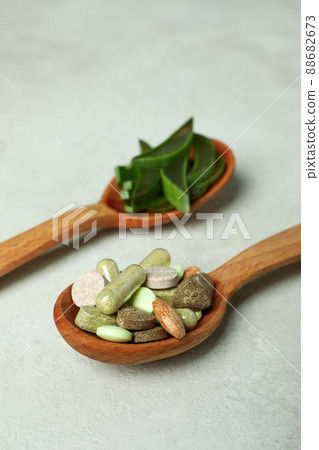 Concept of herb pills with aloe slices on white textured background Concept of herb pills with aloe slices on white textured background 88682673