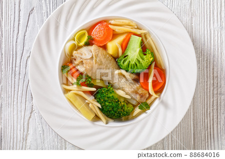 chicken vegetable soup with pasta in white bowl 88684016