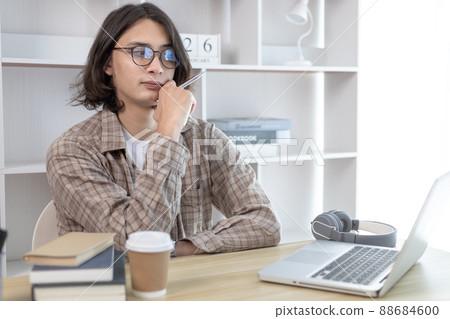 Young studying online uses his laptop in a live performance to communicate with his friends and teachers, Using laptops and data graphs in class, Online communication, Social distancing. 88684600