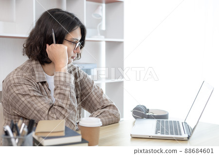 Young studying online uses his laptop in a live performance to communicate with his friends and teachers, Using laptops and data graphs in class, Online communication, Social distancing. 88684601