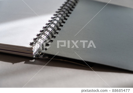 Black spring-loaded notebook against a gray background. Close-up of an open notebook and blank white sheets. Black spring-loaded notebook against a gray background. Close-up of an open notebook and blank white sheets. 88685477