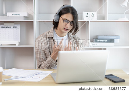 Young Asian men are greeting friends and teachers through video chats and greeting them with cheerful expressions, Online communication , Stay home, New normal, VDO Call, Social distancing, Internet l 88685877