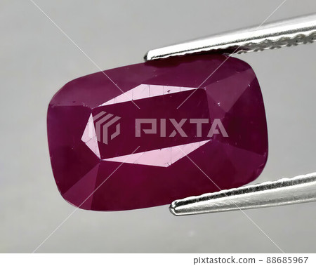 Natural gemstone red ruby in tongs on a gray background 88685967