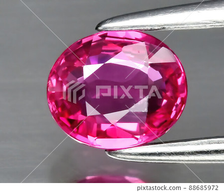 Natural gemstone red ruby in tongs on a gray background 88685972