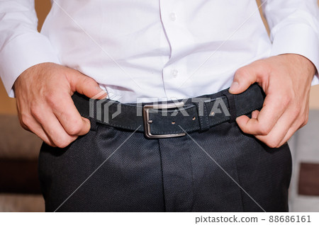 The groom tightens his belt. A man holding his hands on his belt The groom tightens his belt. A man holding his hands on his belt 88686161