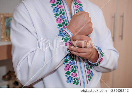 The groom fastens a button on the sleeve of his shirt 88686242