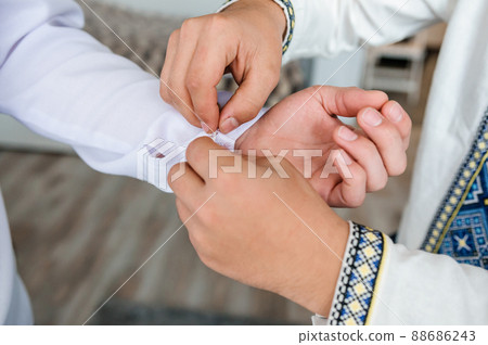 The man fastens the cufflink on the sleeve of his shirt. The groom fastens a button on the sleeve of his shirt The man fastens the cufflink on the sleeve of his shirt. The groom fastens a button on the sleeve of his shirt 88686243
