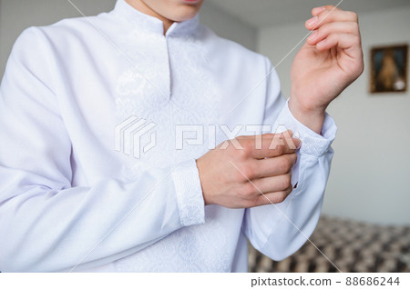 The man fastens the cufflink on the sleeve of his shirt. The groom fastens a button on the sleeve of his shirt The man fastens the cufflink on the sleeve of his shirt. The groom fastens a button on the sleeve of his shirt 88686244