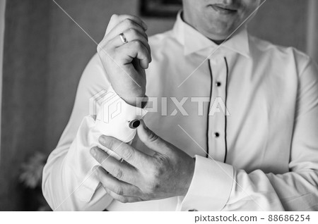 The man fastens the cufflink on the sleeve of his shirt. The groom fastens a button on the sleeve of his shirt 88686254
