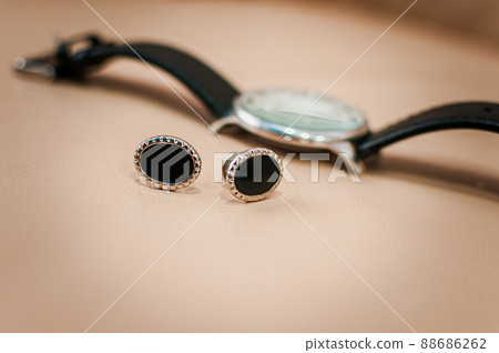 Men's cufflinks and a watch with a black strap on a brown background Men's cufflinks and a watch with a black strap on a brown background 88686262