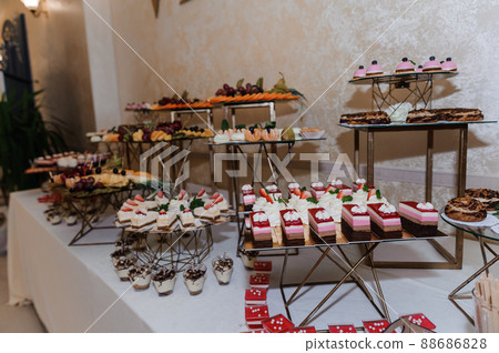Sweet cakes at a wedding banquet. Catering, sweet festive buffet. Candy bar Sweet cakes at a wedding banquet. Catering, sweet festive buffet. Candy bar 88686828