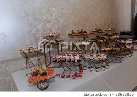 Sweet cakes at a wedding banquet. Catering, sweet festive buffet. Candy bar Sweet cakes at a wedding banquet. Catering, sweet festive buffet. Candy bar 88686830