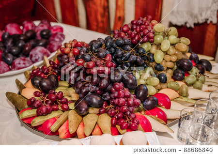Fruit slicing at a wedding banquet. Watermelon, grapes, strawberry, orange, plum, pear, dinha, peach, kiwi, pineapple, persimmon, apple 88686840