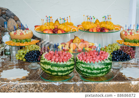 Fruit slicing at a wedding banquet. Watermelon, grapes, strawberry, orange, plum, pear, dinha, peach, kiwi, pineapple, persimmon, apple 88686872