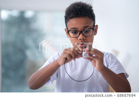 A waist up picture of a boy with a usb cable in hands 88687694