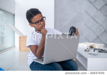 A cute teen sitting at the laptop and looking involved 88687698